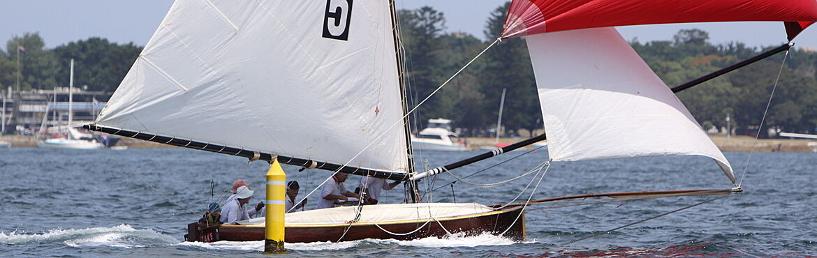 Sailing wooden vintage yacht with white sails and red spinnacker